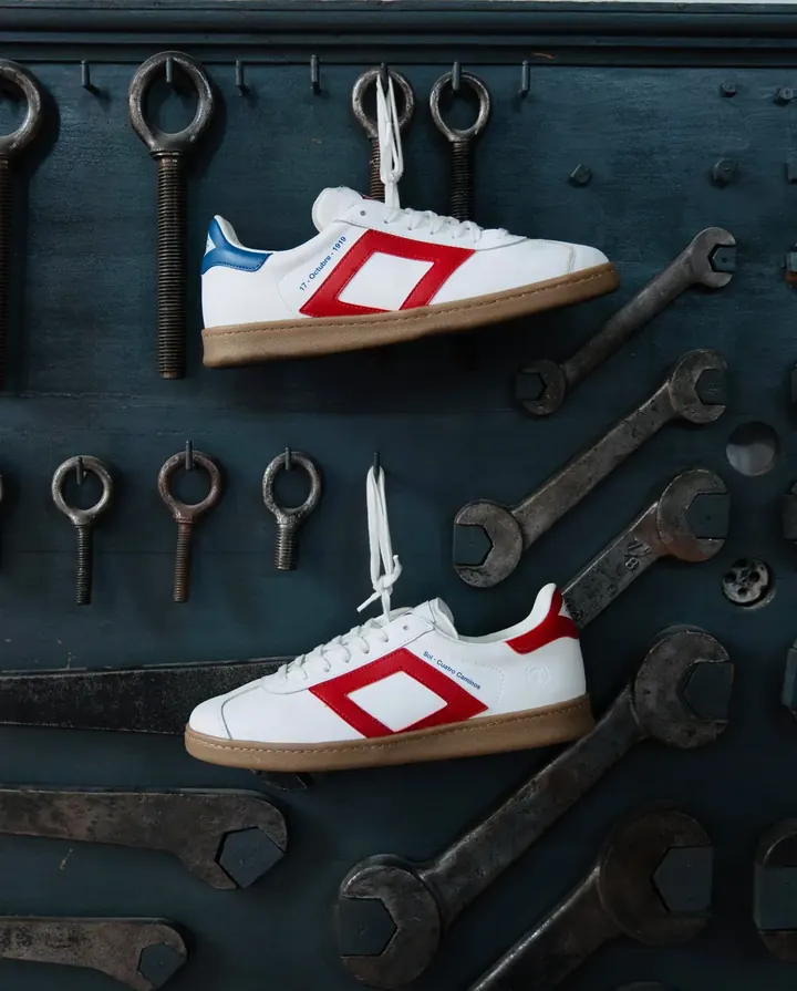 Zapatillas blancas con el rombo rojo del Metro de Madrid colgadas entre llaves inglesas
